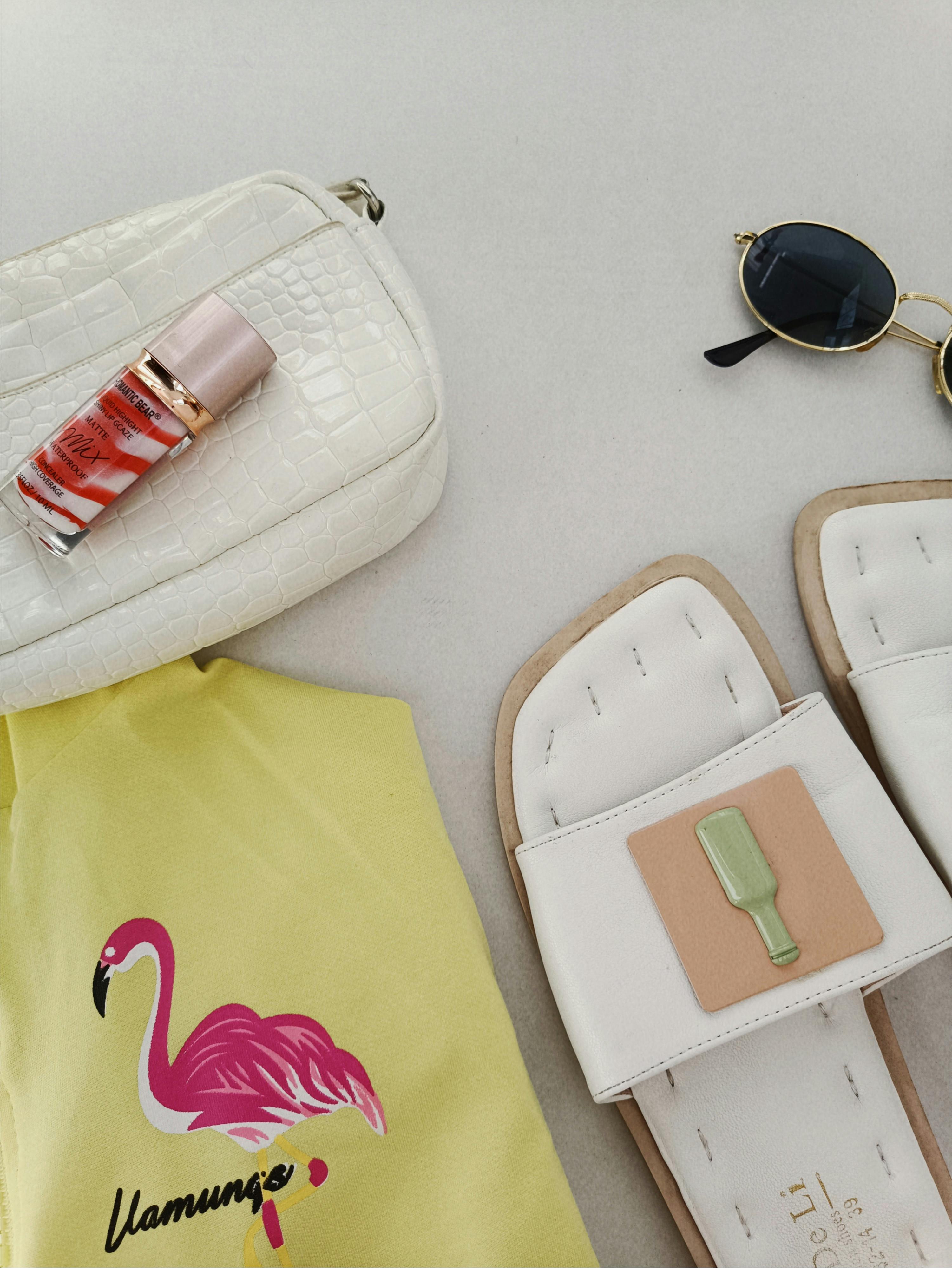 Flat lay of summer accessories: sandals, sunglasses, and cosmetics for a trendy look.