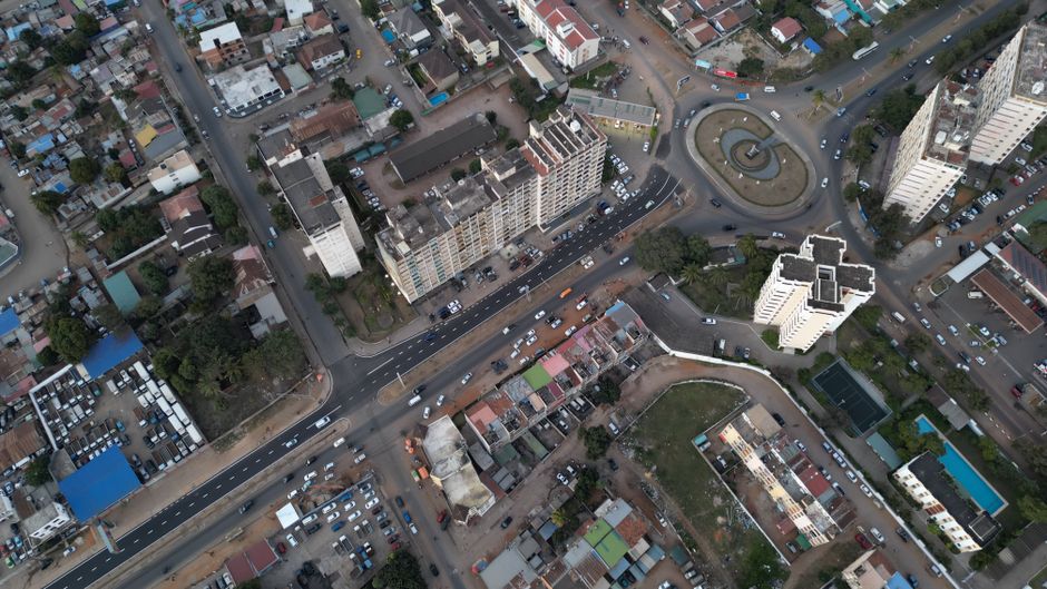Aerial shot of Maputo cityscape featuring buildings, roads, and roundabout.
