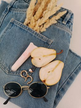 Fashionable flat lay showcasing denim, pear slices, sunglasses, and accessories.