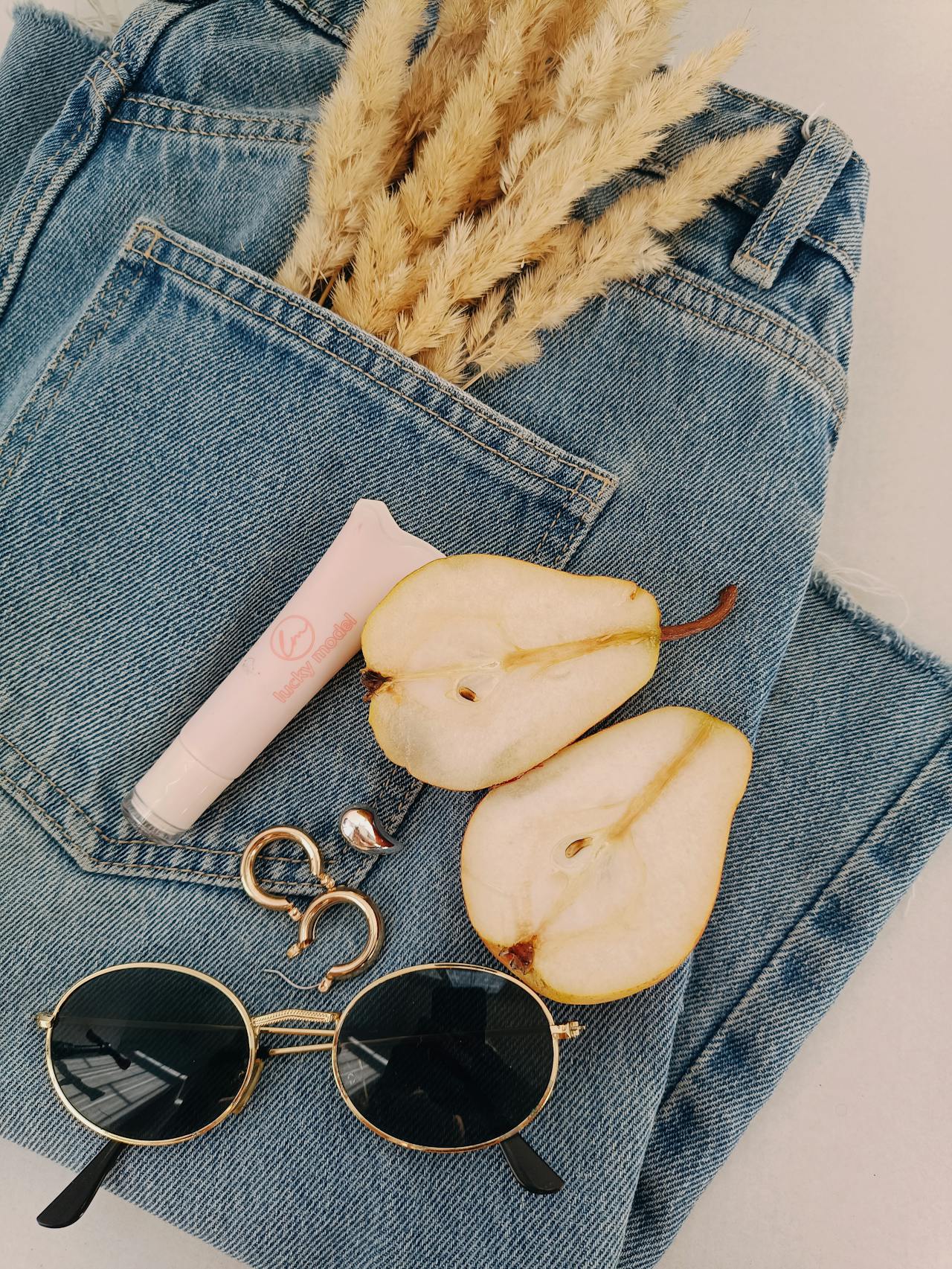 Flat lay con denim, accessori e sfondo luminoso minimalista