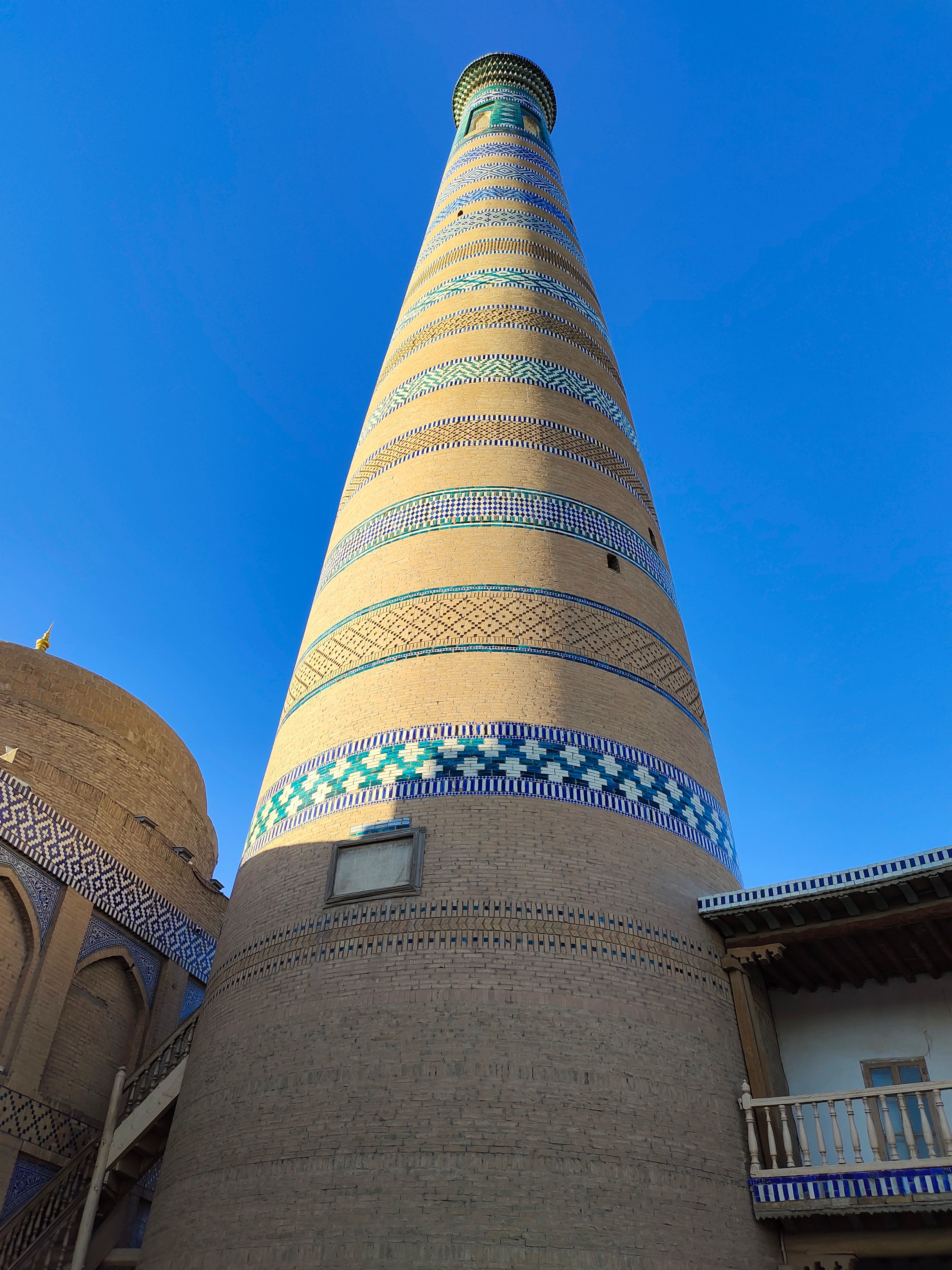 A vibrant view of a historic minaret against a clear blue sky in Khiva, capturing architectural elegance.