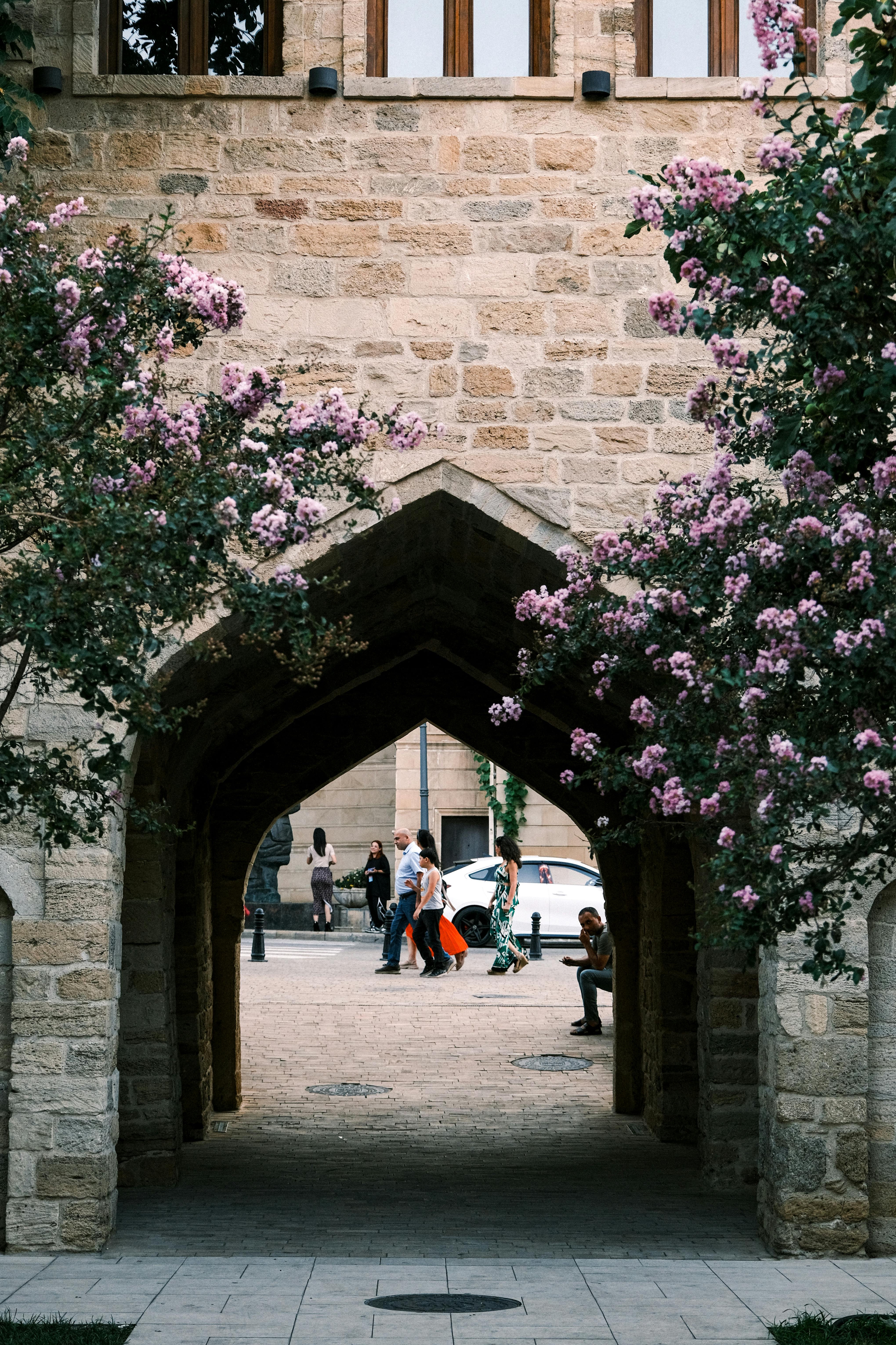 Picturesque view through archway framed by blooming trees, stone walls enhance historic charm.