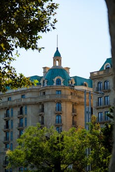 A classic building with green domes surrounded by trees, showing intricate architectural design.