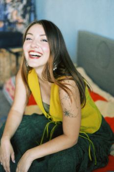 Cheerful woman in Baku, Azerbaijan, wearing a vibrant summer dress and showcasing a tattoo, expressing joy.