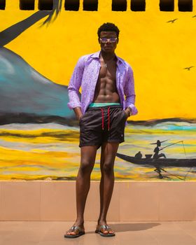 Fashionable young man stands against a colorful mural in Osogbo, exuding summer vibes.