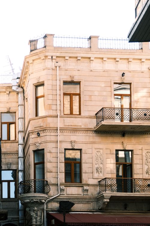 Free Elegant European stone building with ornate balconies in soft daylight. Stock Photo
