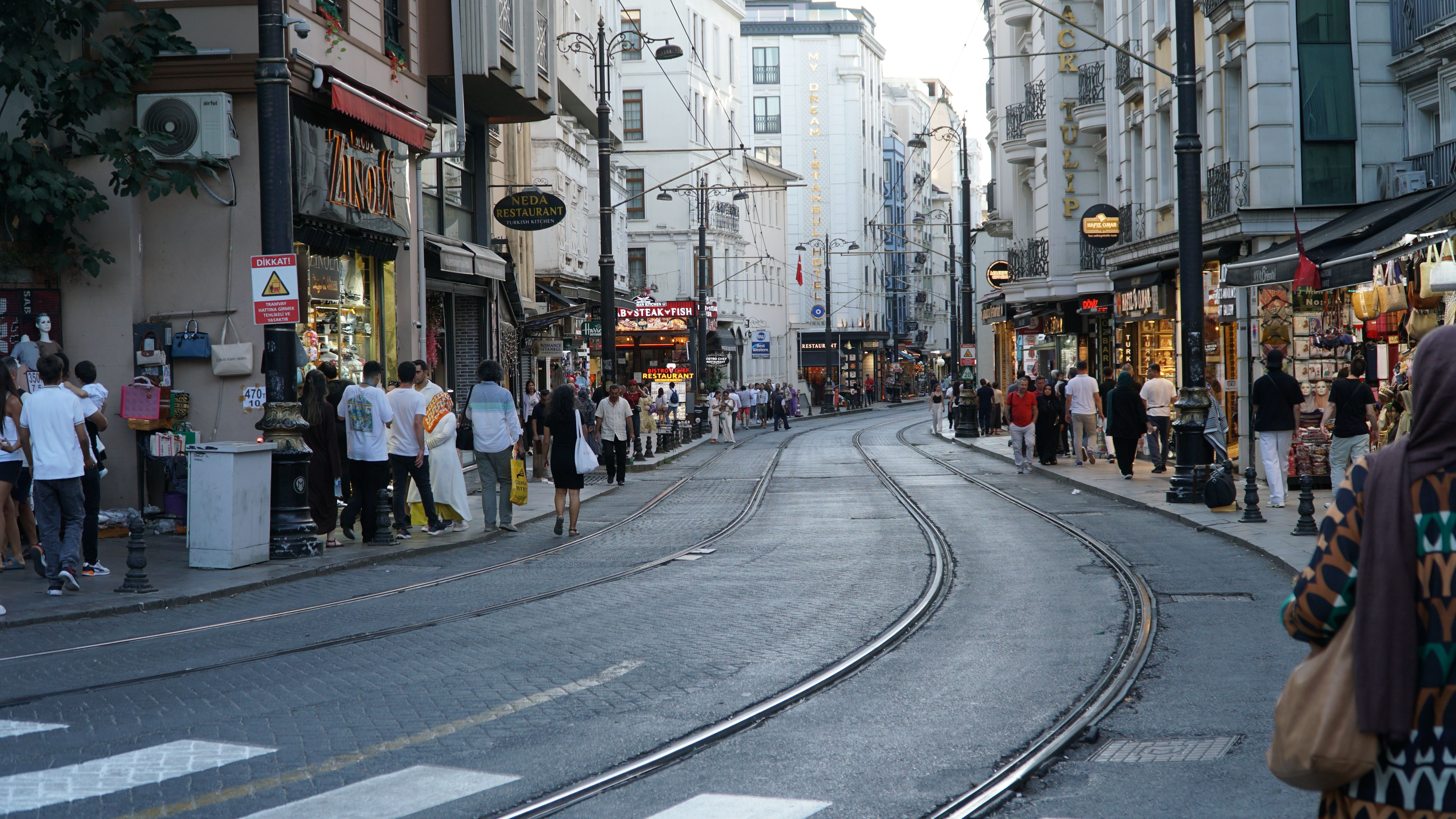 Vibrant street scene showing people shopping on a busy Istanbul street with tram tracks.