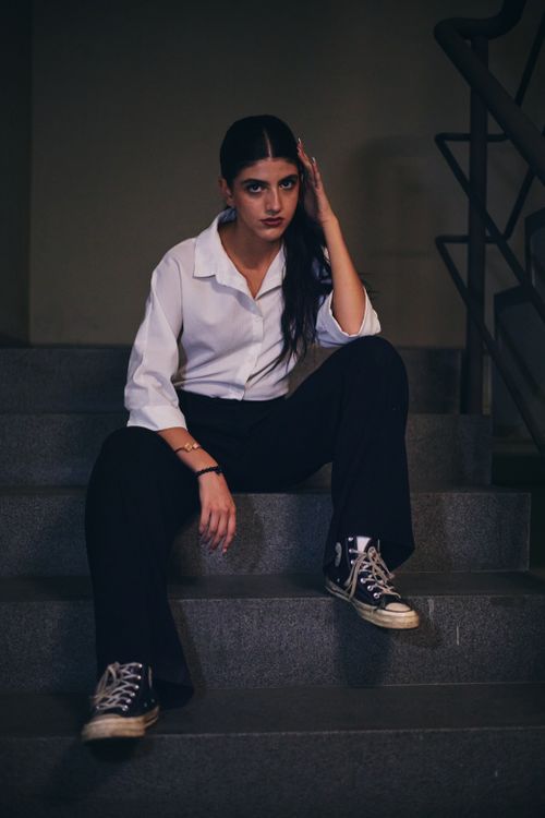 Free Fashionable woman in white shirt sitting on stairs in Istanbul, showcasing a modern and casual look. Stock Photo