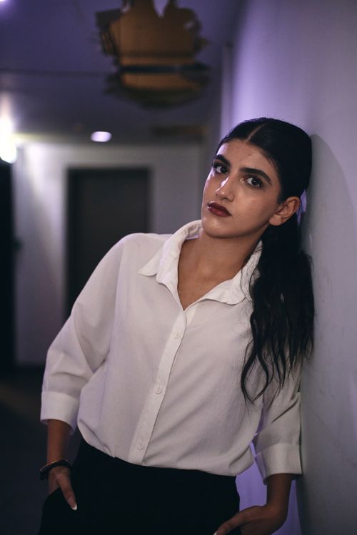 Free Elegant portrait of a young woman in a white shirt leaning against a wall. Stock Photo