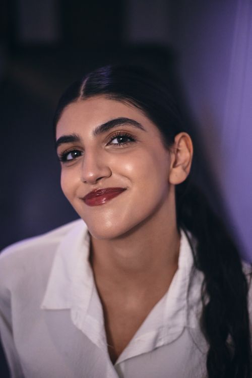 Free A woman in a white shirt smiling warmly in a dimly lit room, capturing a candid moment. Stock Photo