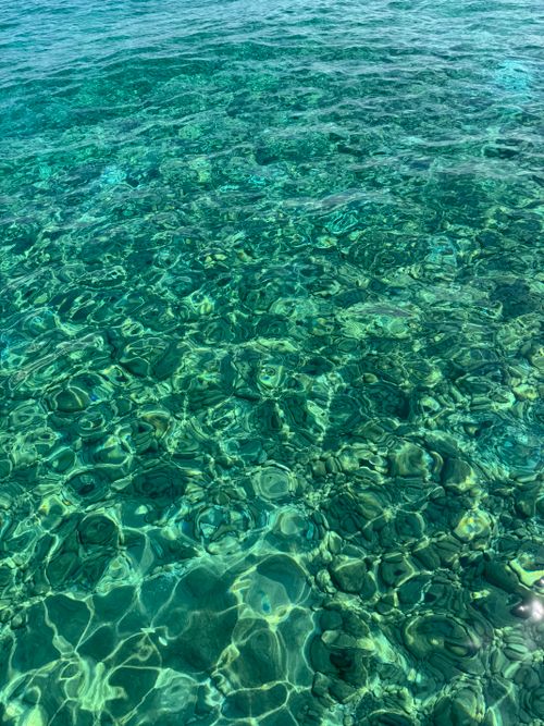 Free Close-up of vibrant turquoise ocean water with rippling patterns reflecting sunlight. Stock Photo
