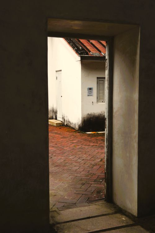 Free View of a rustic Taiwanese alleyway captured through a doorway with textured walls. Stock Photo