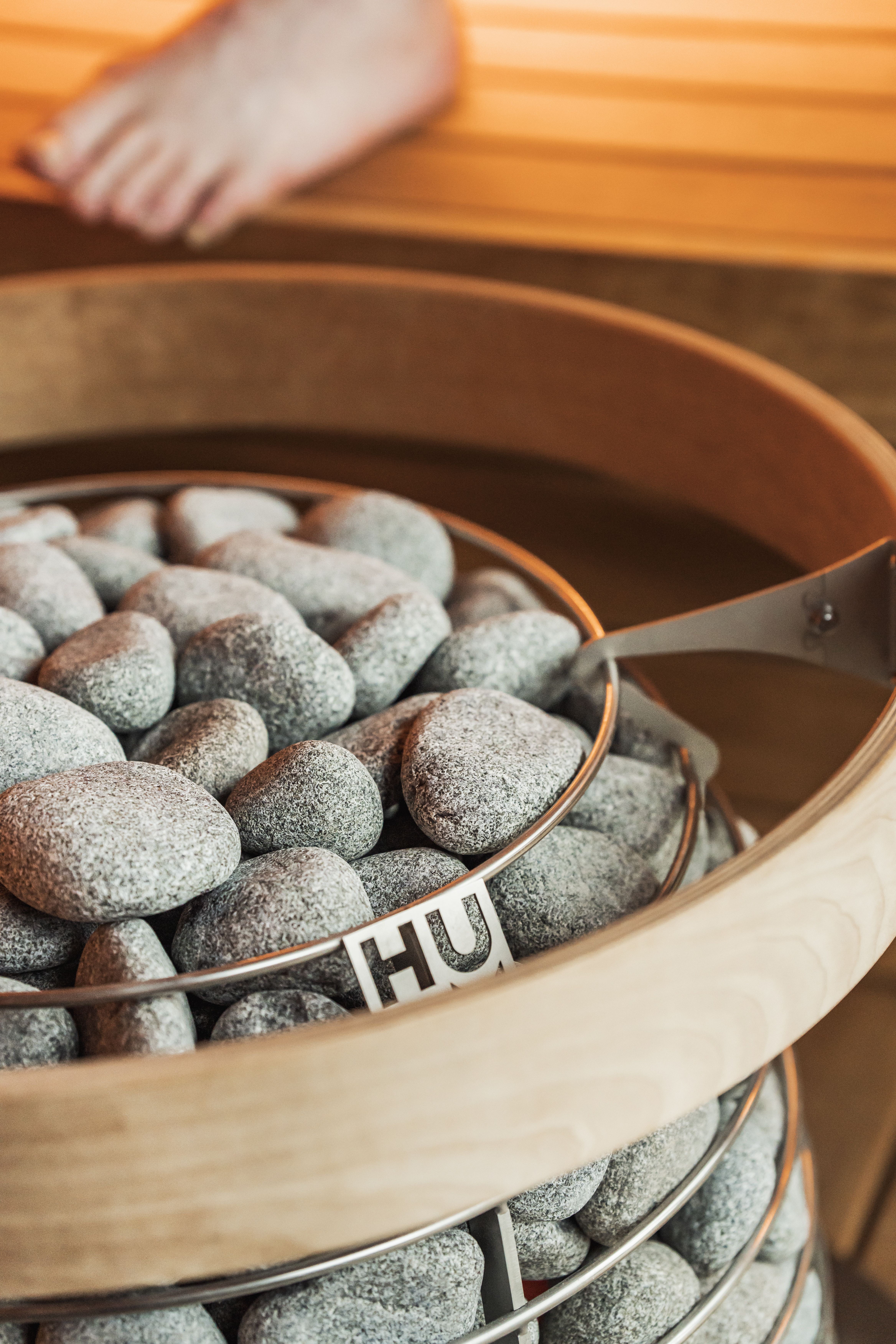 Close-up of a HUUM sauna heater with stones in a Nordic-style sauna, promoting relaxation and wellness.
