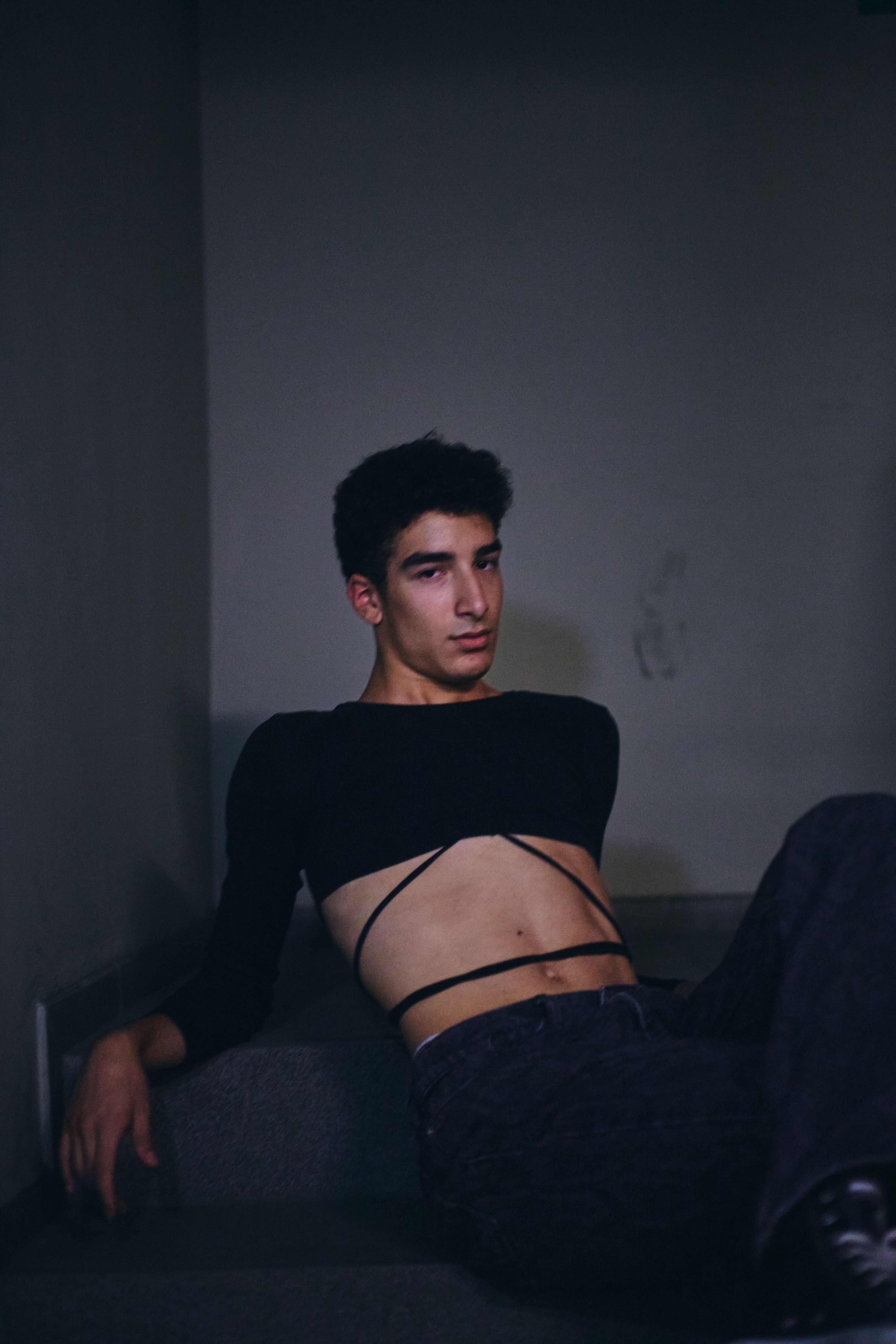 Artistic portrait of a young man in modern fashion, captured indoors with a moody tone.