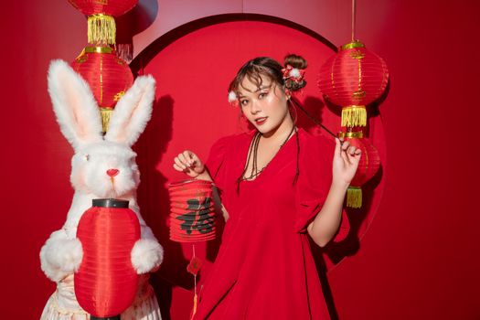 Young woman in red dress with rabbit and lanterns celebrates Lunar New Year.