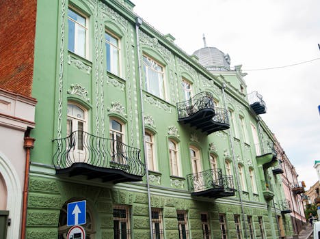 Charming green building with ornate balconies and detailed architecture in an urban street.