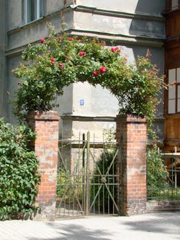 A vintage brick archway adorned with vibrant red roses at a classic building entrance.