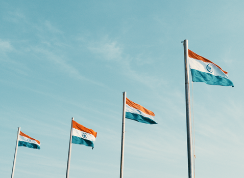 Four Indian flags waving against a clear blue sky, symbolizing patriotism.