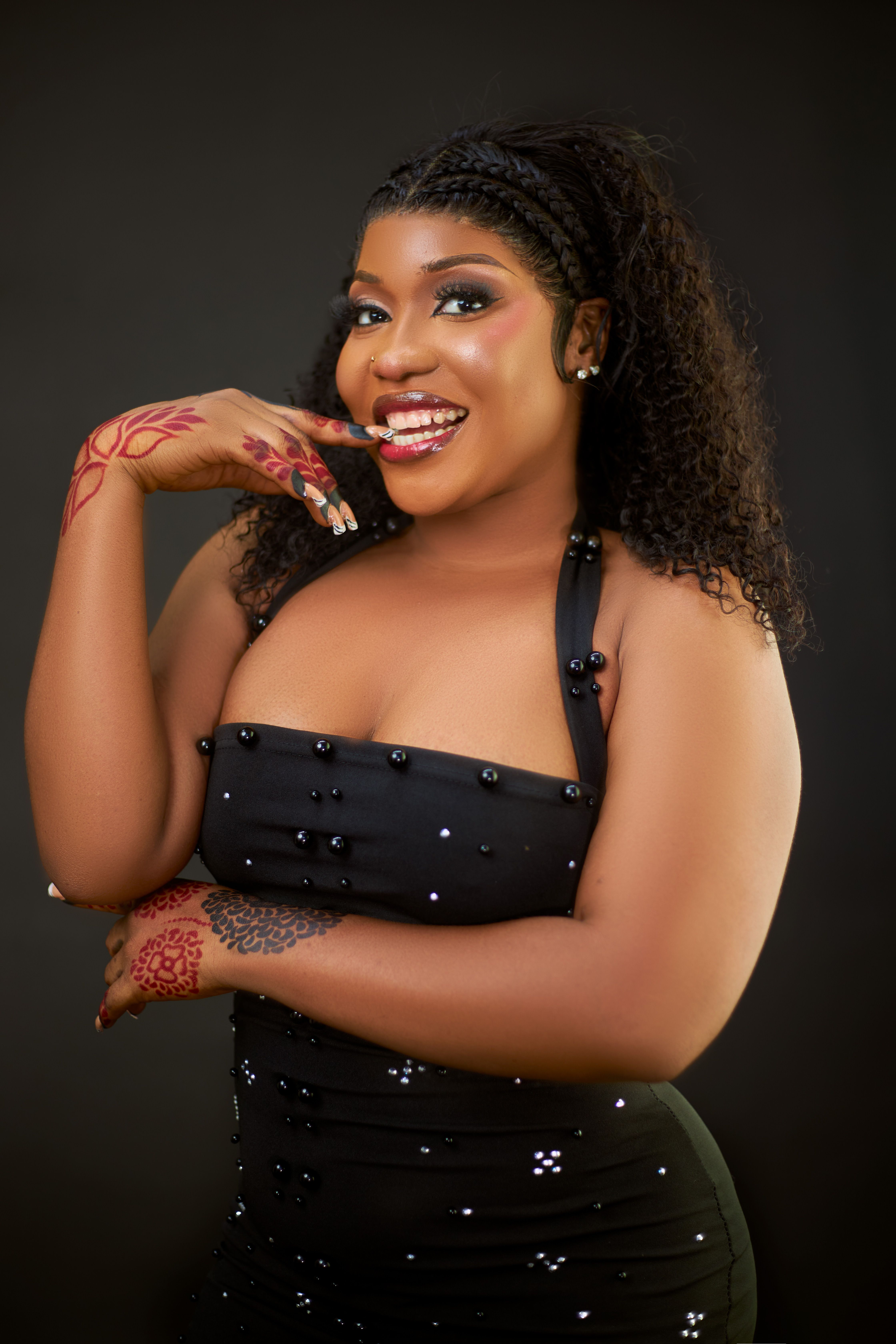Portrait of a joyfully smiling woman in an elegant black dress adorned with beads, showcasing intricate henna art on her hands.