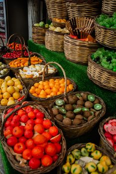 A vibrant display of assorted fruits in wicker baskets at an outdoor market stall.