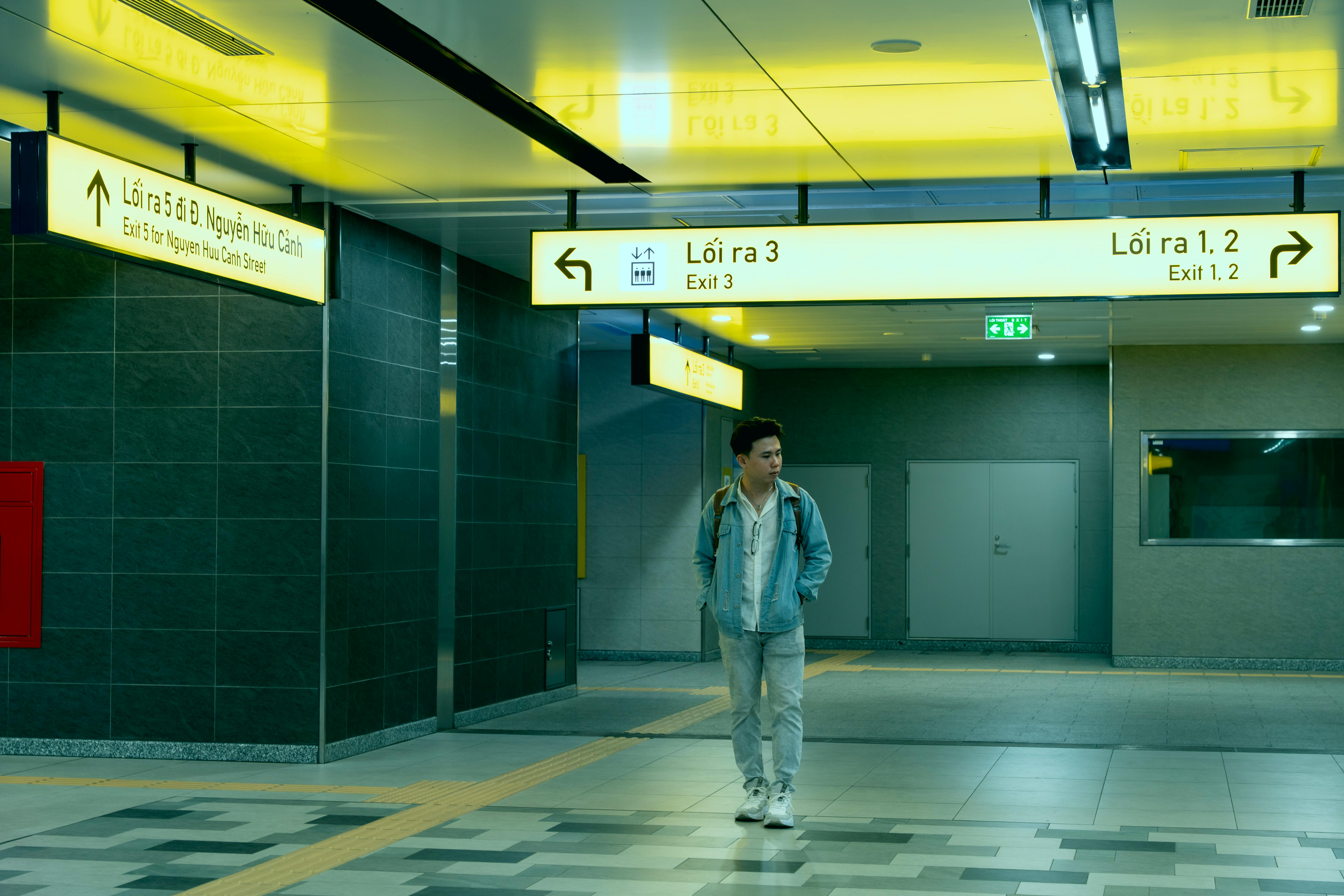 A man walks through an illuminated underground subway station featuring modern design and signage.