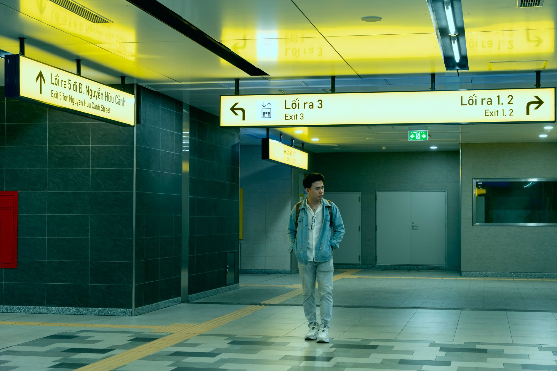 A man walks through an illuminated underground subway station featuring modern design and signage.
