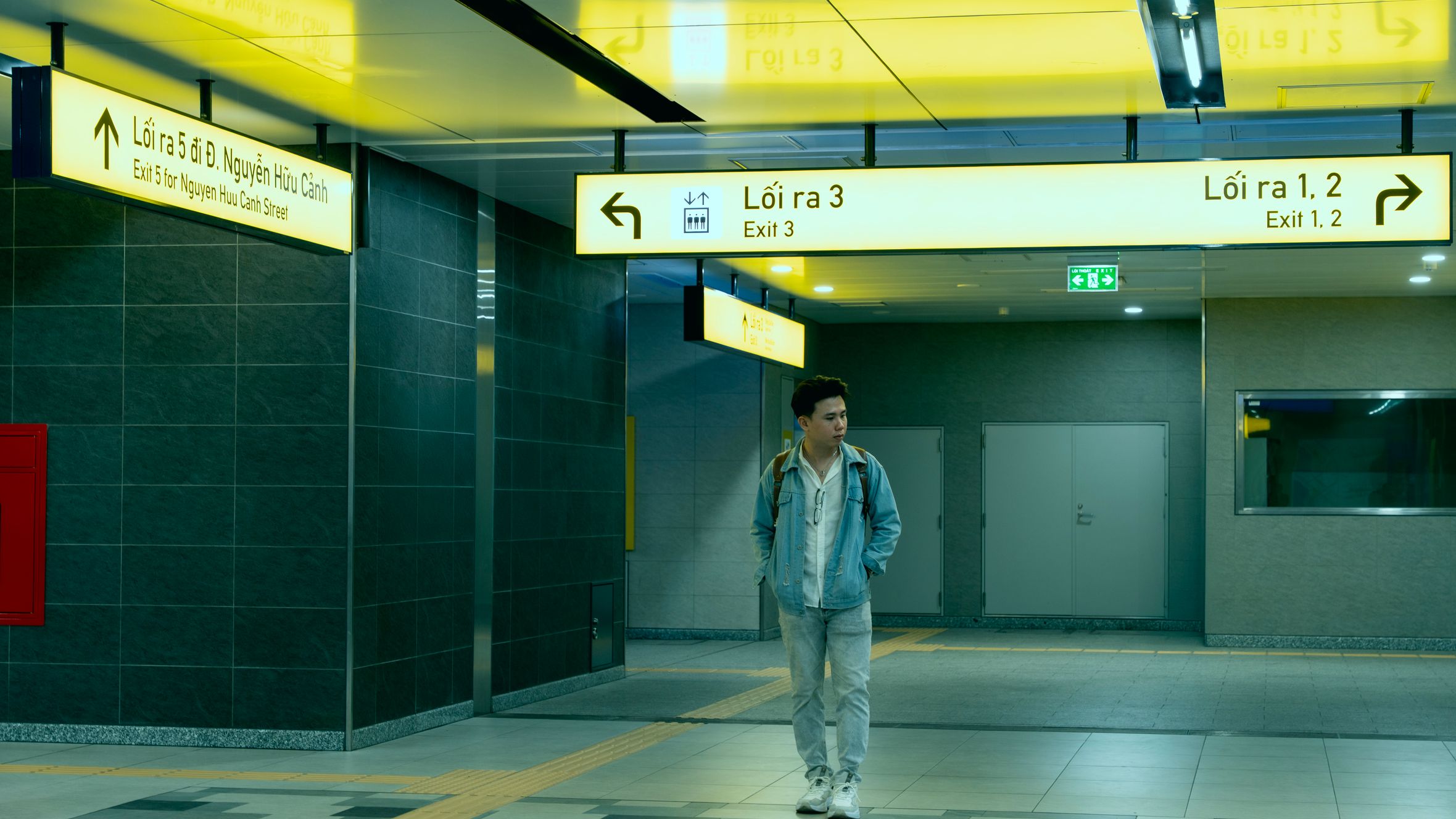 A man walks through an illuminated underground subway station featuring modern design and signage.