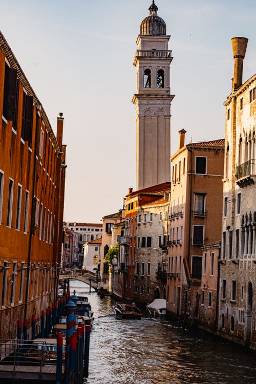 Free Scenic view of a Venetian canal with historic architecture and bell tower at sunset in Venice, Italy. Stock Photo