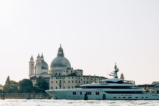 Yacht sailing past Santa Maria della Salute basilica in Venice, Italy. Iconic architecture meets modern luxury.