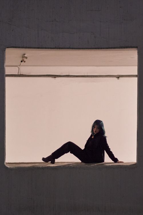 Free Fashionable blue-haired model posing in a minimalist industrial indoor space, showcasing edgy modern style. Stock Photo