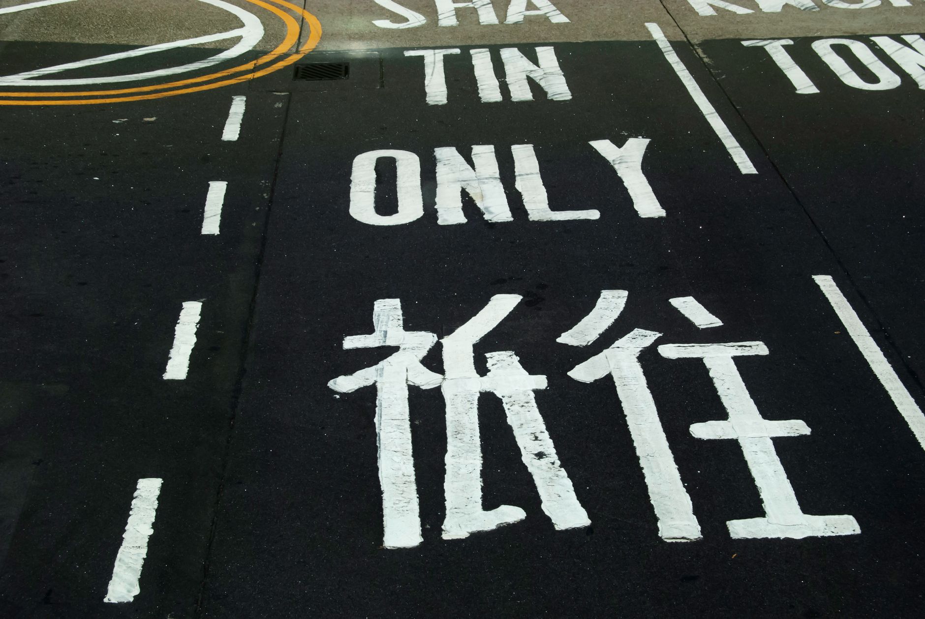 Bilingual road marking in Sha Tin, directing traffic, captured in street photography style.