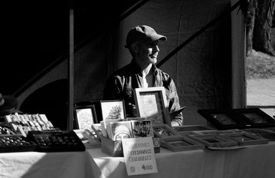 Black and white photo of an artisan vendor at a street market in La Plata, Argentina.