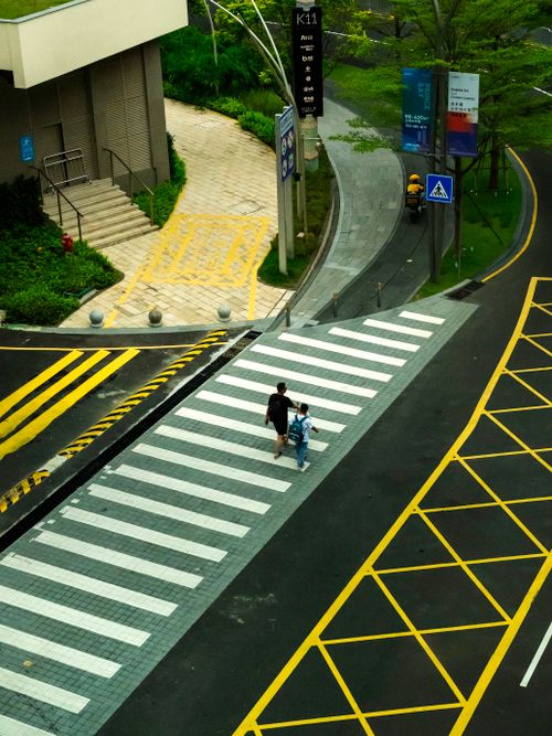 Free Aerial view of people crossing a city road at a marked pedestrian crosswalk. Stock Photo
