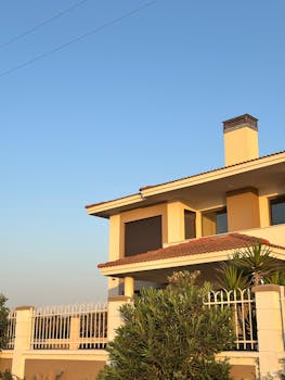 Modern two-story house with fence and clear sky background.