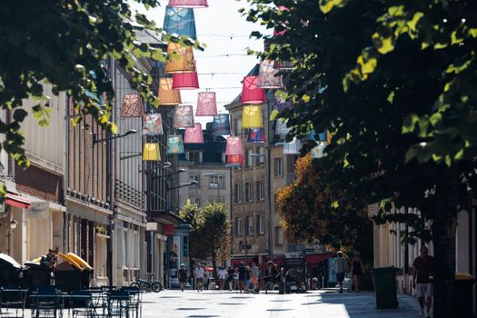 Colorful street scene with hanging lanterns in Amiens, showcasing European architecture.