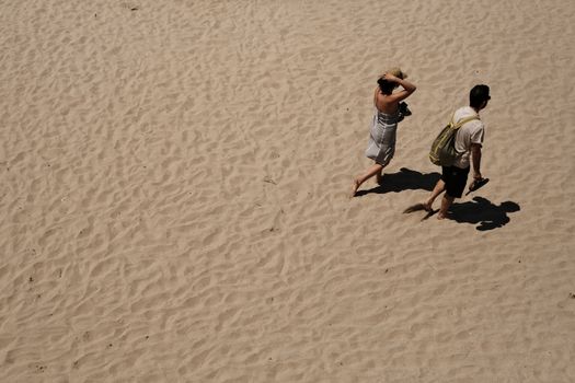 A couple walks along the sunny Esposende beach in Portugal, leaving footprints in the sand.