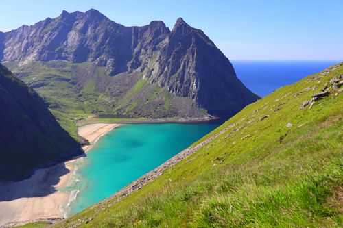 Free Vibrant coastal landscape of a secluded beach with turquoise water surrounded by towering mountains. Stock Photo