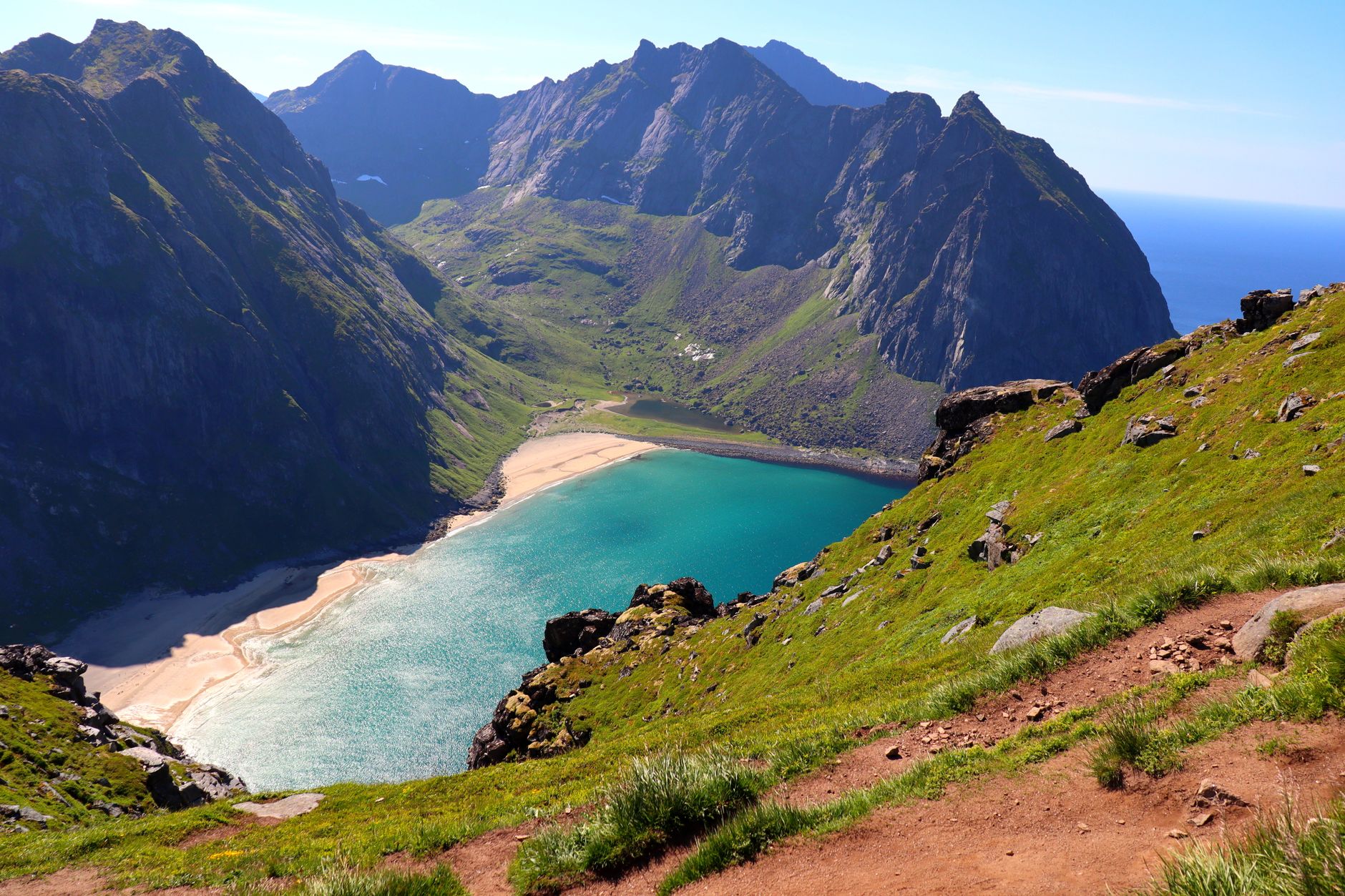 Breathtaking aerial view of Kvalvika Beach surrounded by mountains and clear sea in Norway.