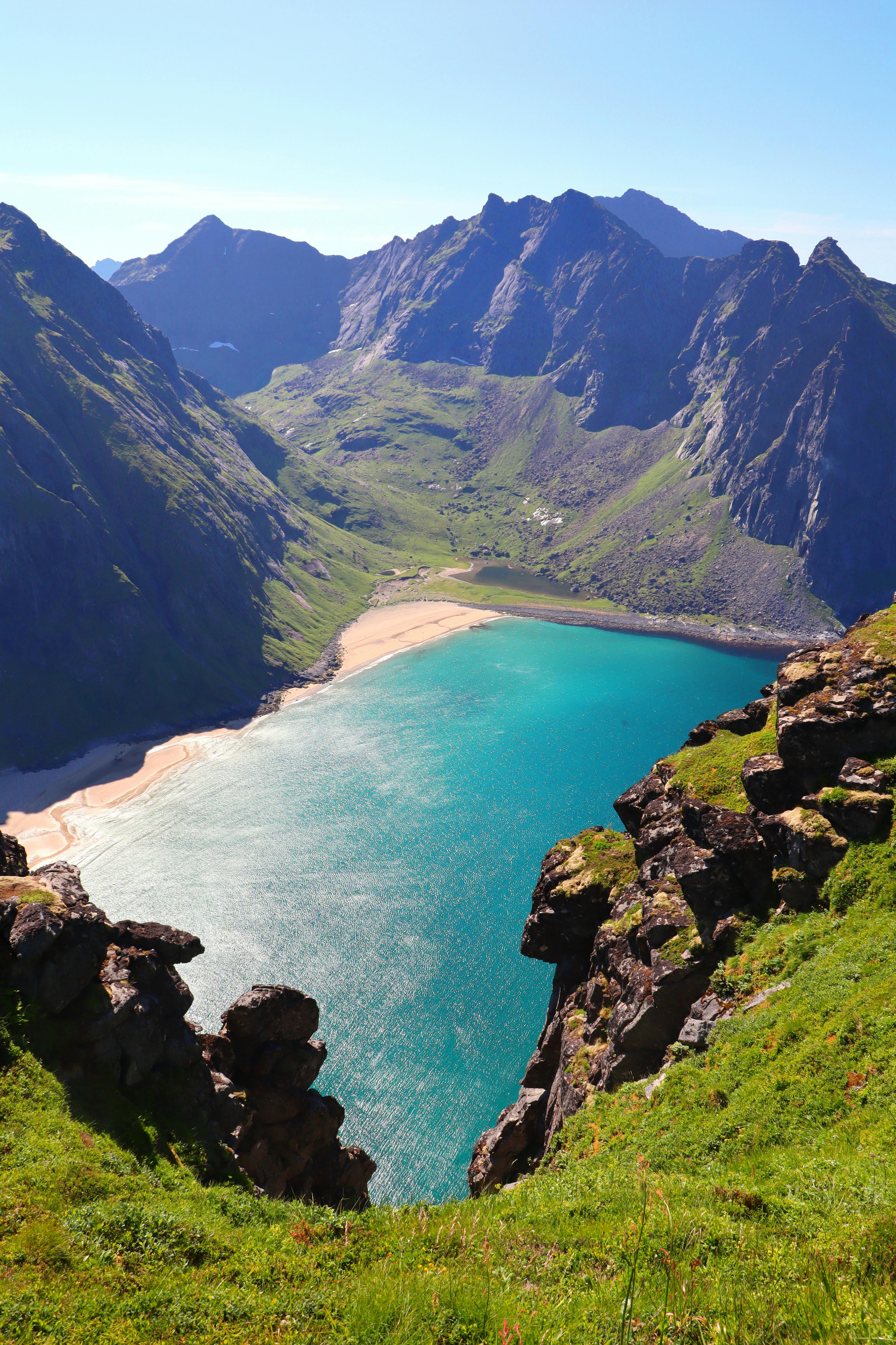 A stunning aerial view of Kvalvika Beach nestled amidst Lofoten's rugged mountains.