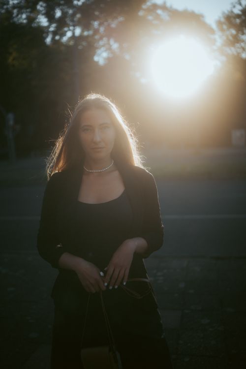 Free A mysterious young woman stands in the warm glow of sunset in Berlin. Stock Photo