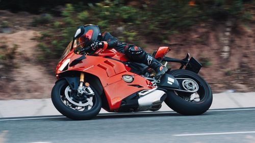 Free Red motorcycle racing swiftly on a scenic outdoor road curve. Stock Photo