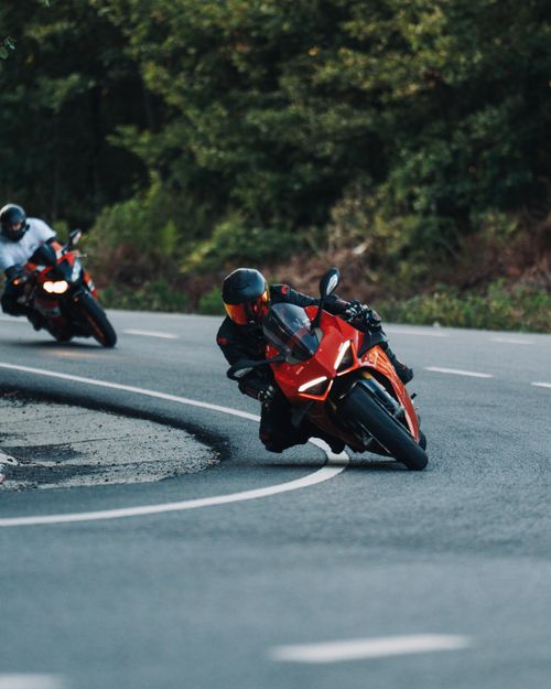 Free Two motorcyclists navigate a sharp turn on a scenic road, showcasing speed and precision. Stock Photo