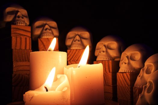 A dark and spooky still life of glowing candles and skulls, perfect for Halloween themes.
