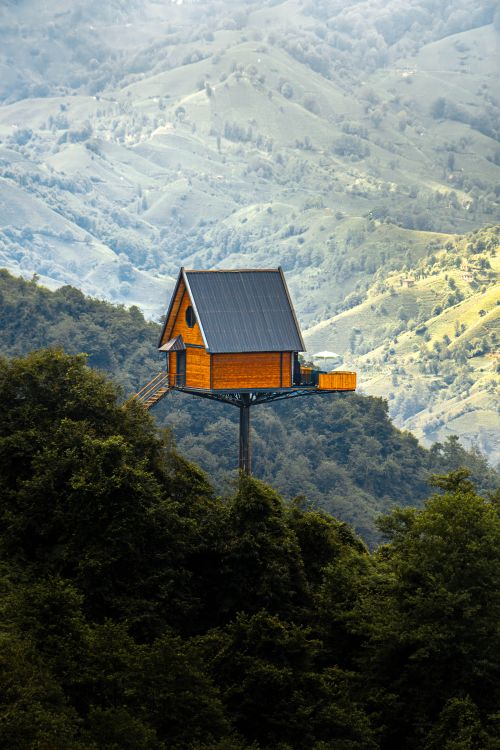 Free A wooden treehouse perched on a mountain with lush green scenery. Stock Photo