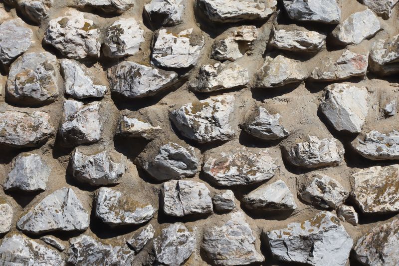 Detailed texture of a rustic stone wall with irregular white stones for architectural backgrounds.