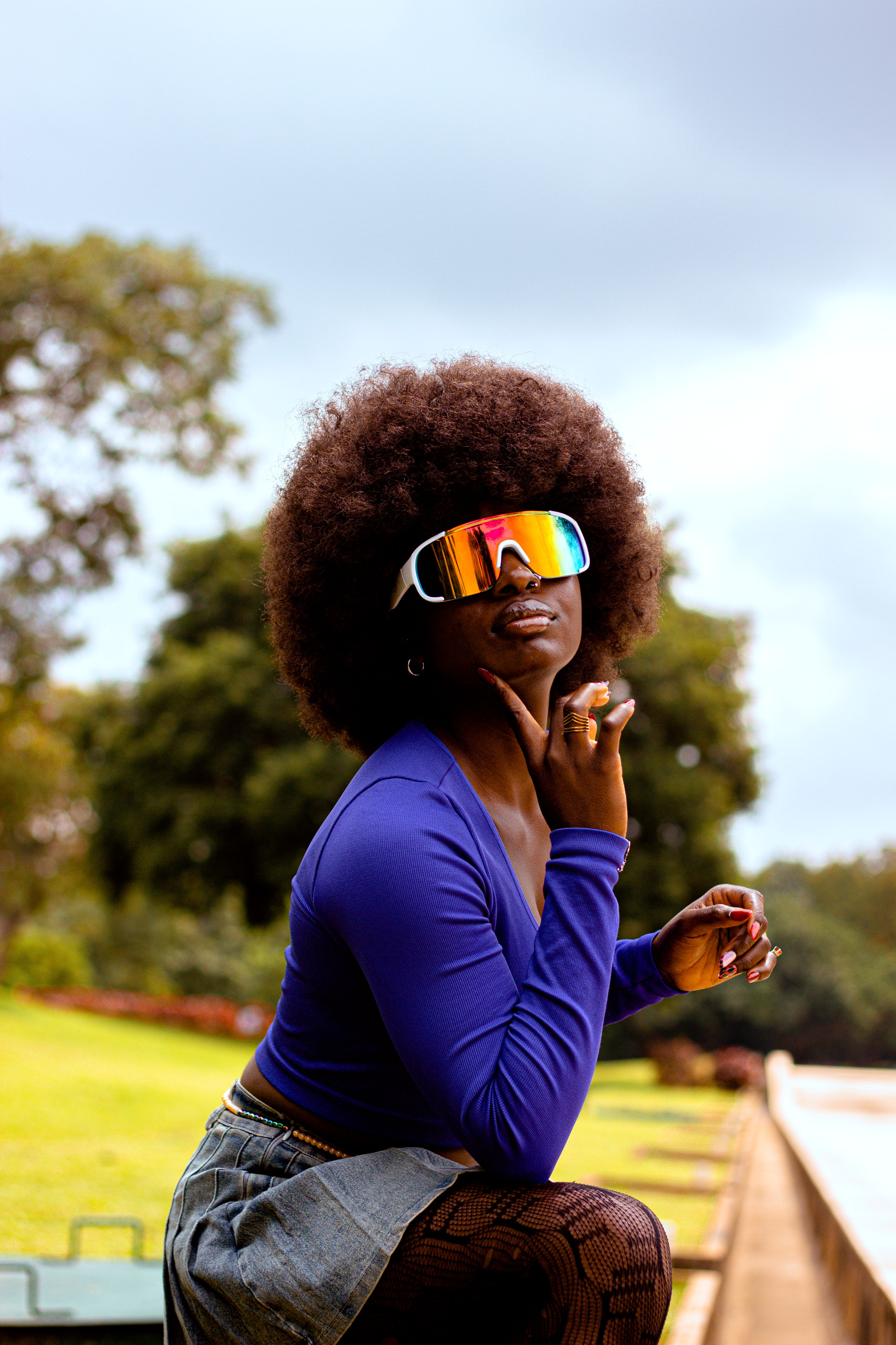 Afro hairstyle woman wearing futuristic glasses outdoors, showcasing fashion and style.