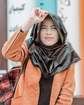 一位头戴头巾、身着橙色外套的女士面带微笑，展现出时尚的户外造型