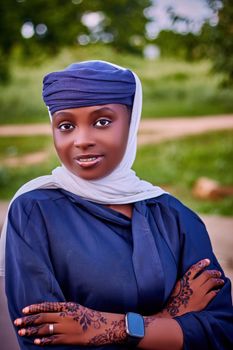Beautiful outdoor portrait of a Nigerian woman in traditional attire with henna designs, showcasing cultural elegance.