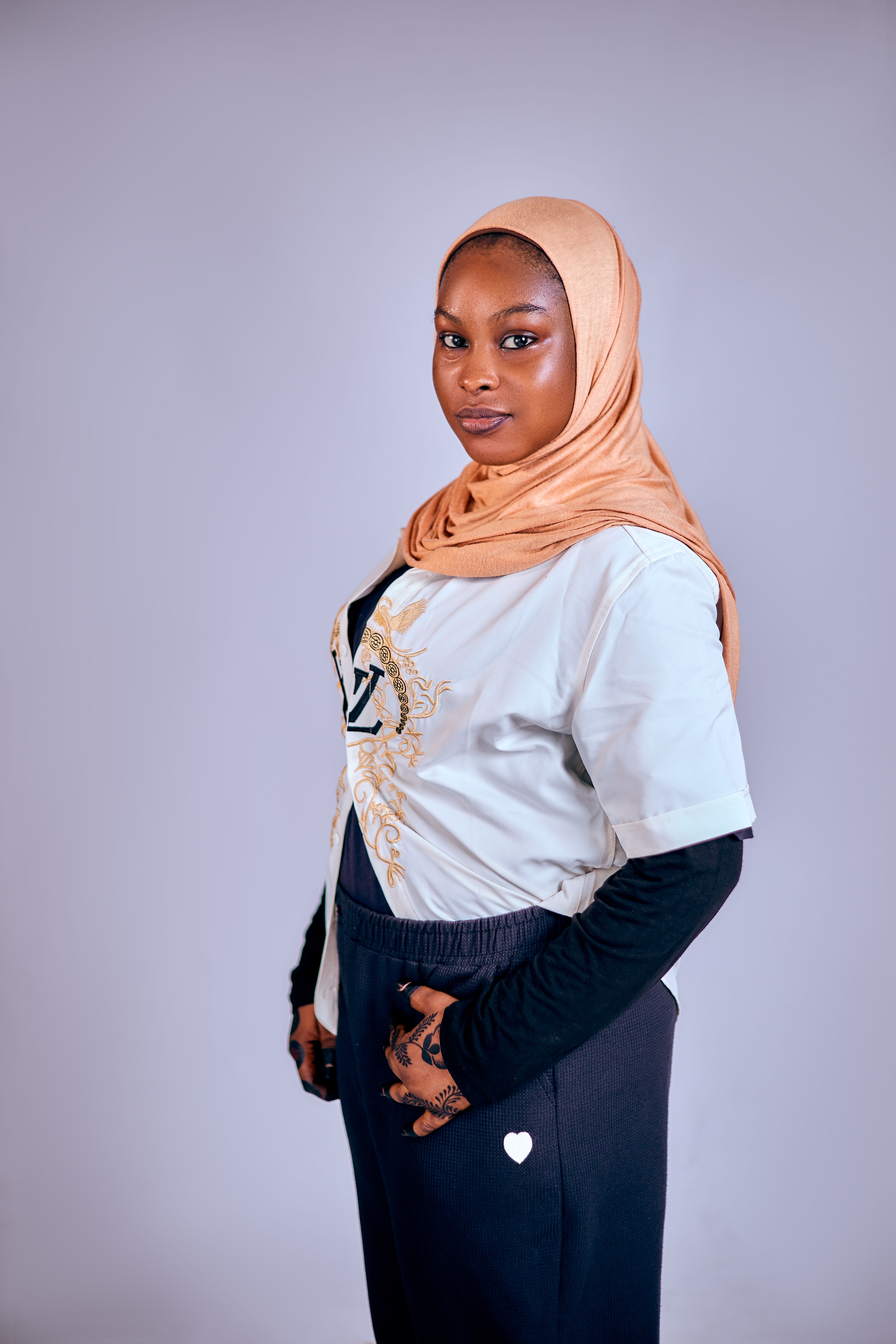 Elegant woman wearing a hijab and casual outfit, exuding confidence in a studio setting.