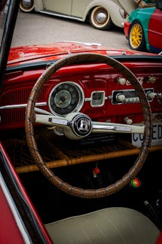 Classic vintage car dashboard featuring a red interior and iconic steering wheel.